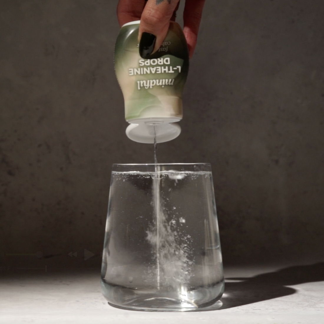 Mindful Drops liquid L-theanine being added to a glass of water, dispersing evenly throughout the drink.