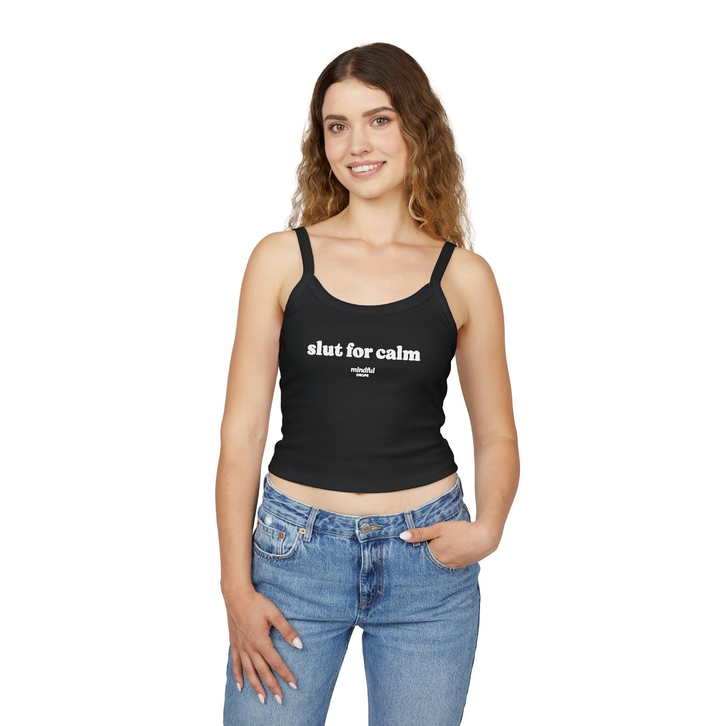 Woman wearing a black tank top with 'slut for calm' text and blue jeans on a white background