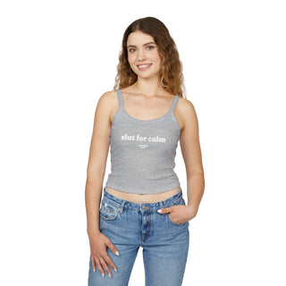 Woman wearing a gray tank top with 'slut for calm' text and blue jeans on a white background