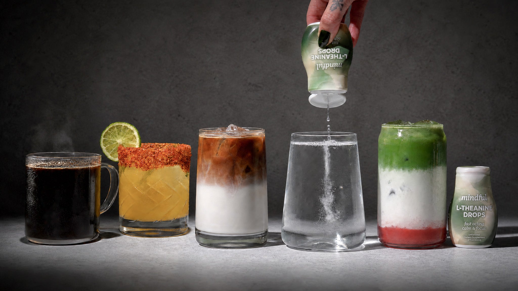 Hand squeezing Mindful Drops, a flavor-neutral liquid L-theanine supplement, into a variety of beverages including coffee, sparkling water, and matcha.
